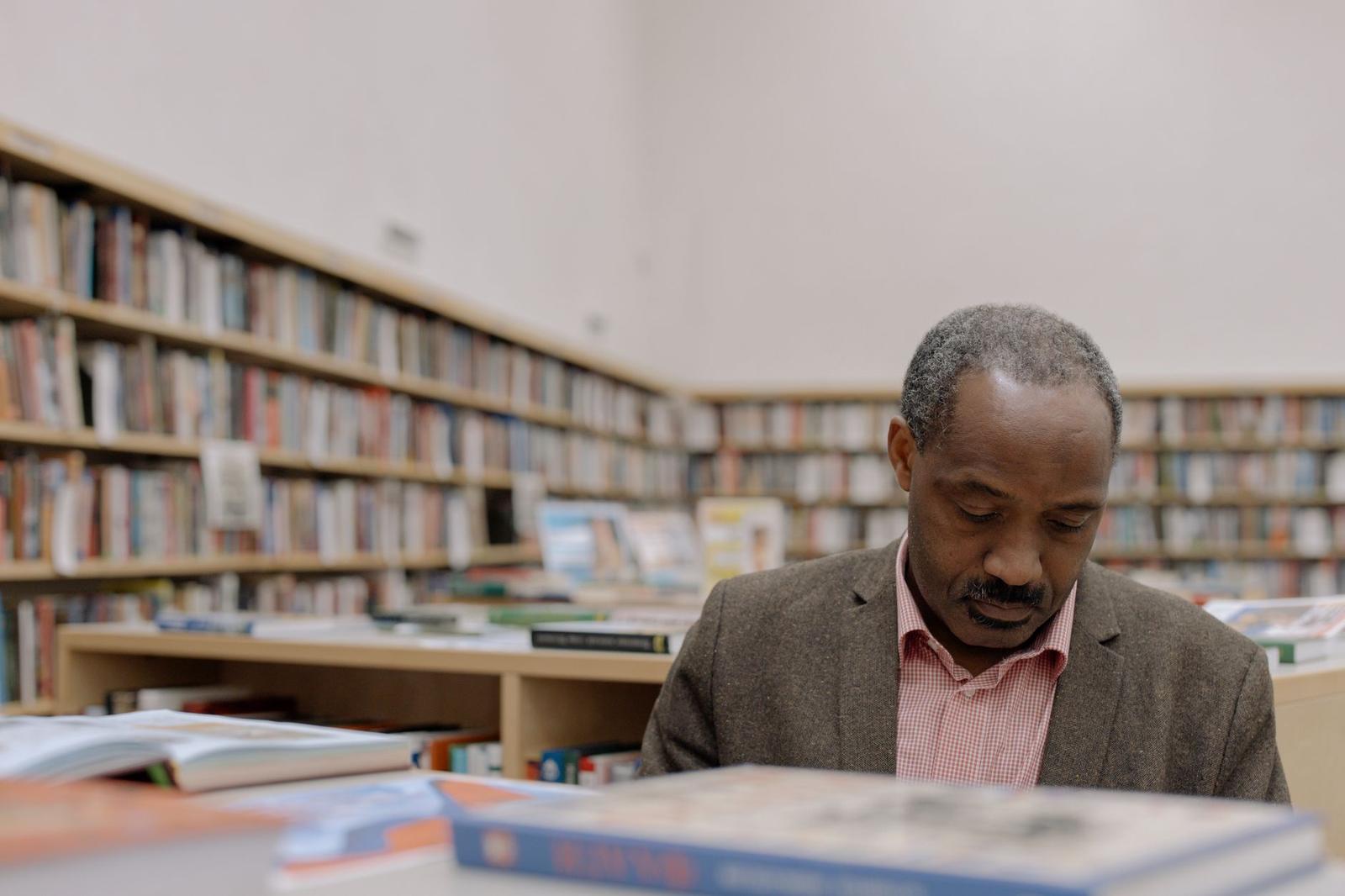 A Man in Gray Suit Jacket Reading a Book
